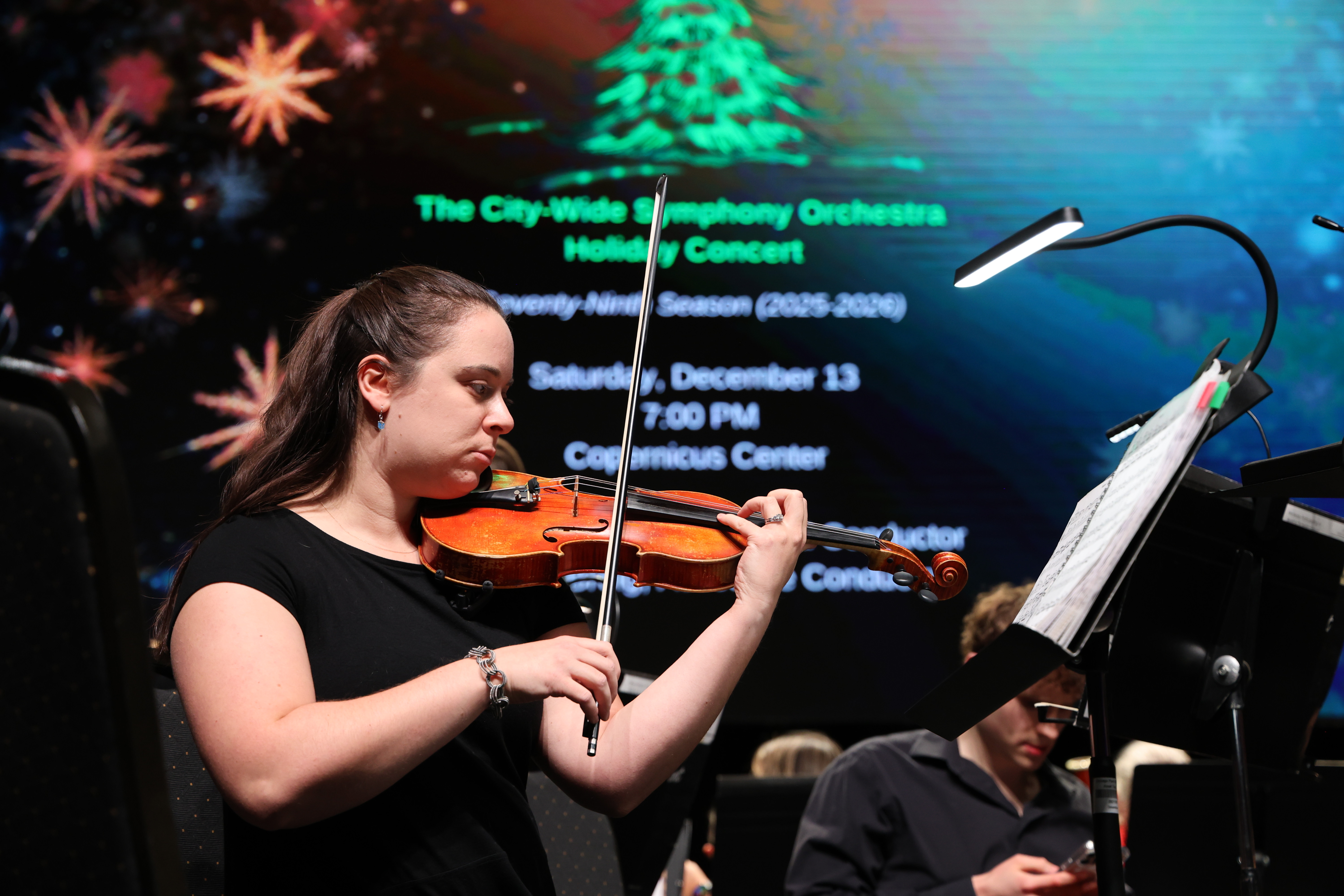Woman playing violin at holiday concert, photograph.